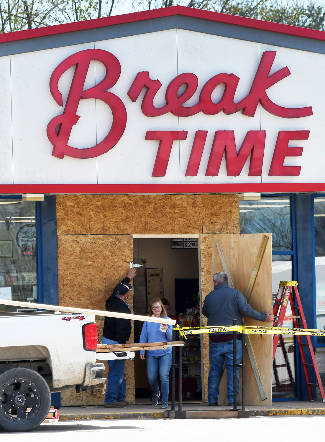 A CUSTOMER exits Break Time on Monday as MFA maintenance employees from Columbia install a temporary front door to the building damaged Sunday evening by a motorist’s car.
